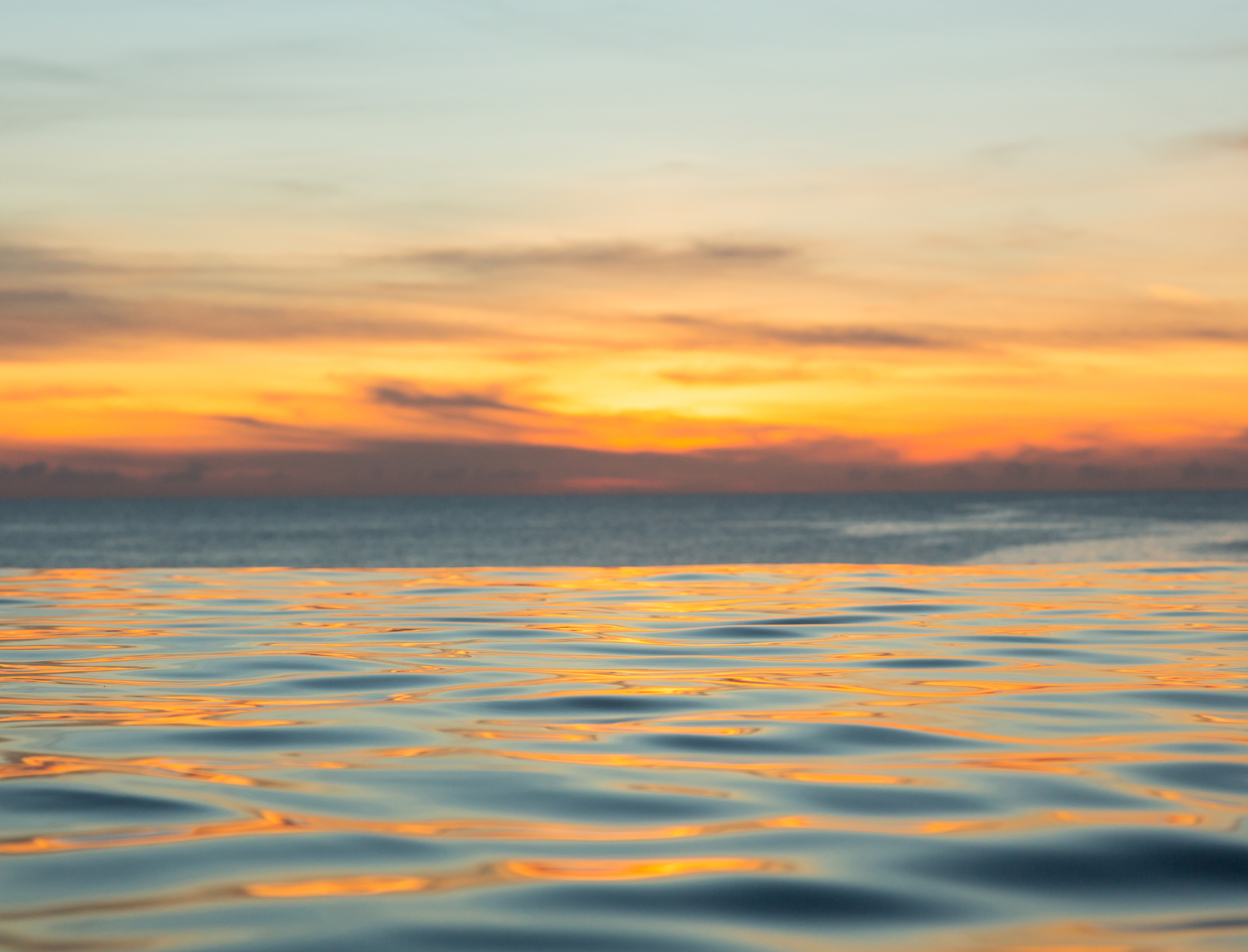 Infinity edge pool with sea underneath sunset
